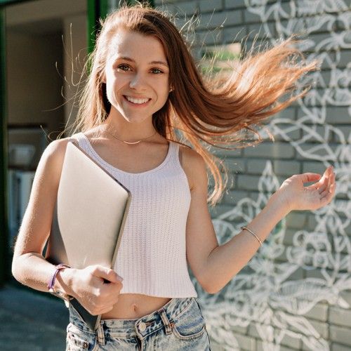 Ein junges Mädchen mit Laptop unter dem Arm