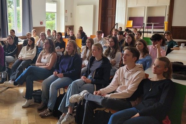 Gruppe von Jugendlichen sitzt aufmerksam in einem Raum und hört einer Präsentation zu.